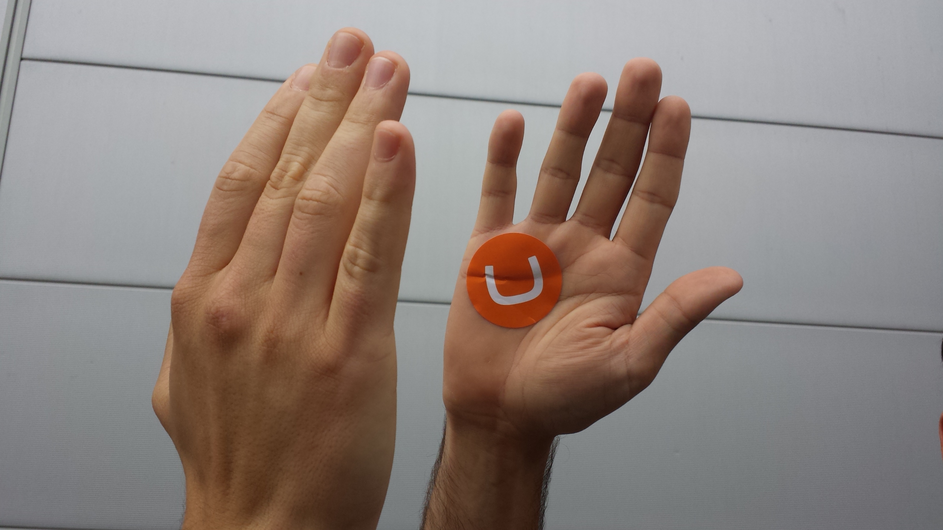 Hands clapping with an orange Umbraco logo sticker in one hand.