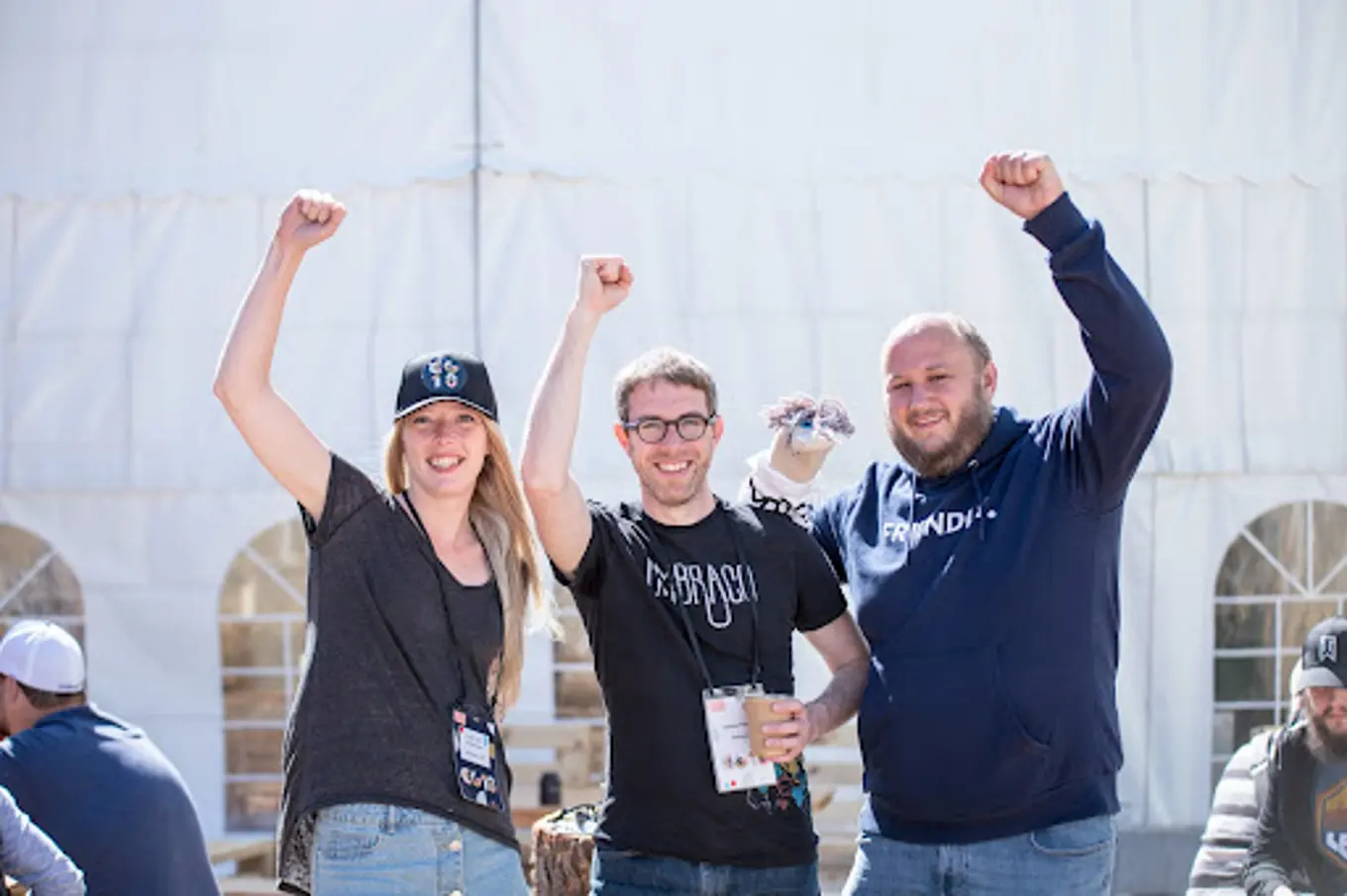 Part of the Docs team - Sofie, Damiaan and Jeavon, have their fists triumphantly in the air. Jeavon is holding a sock puppet.