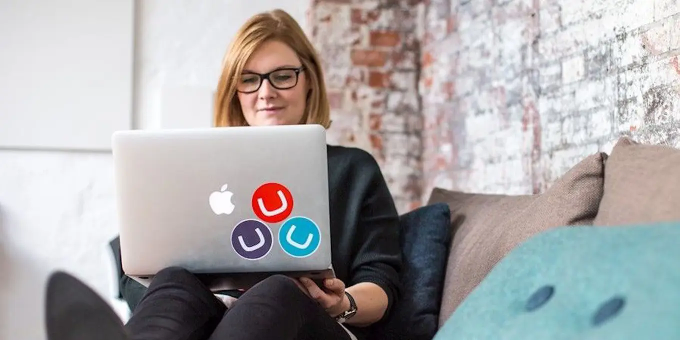 Woman reclining with a Mac laptop covered in Umbraco stickers