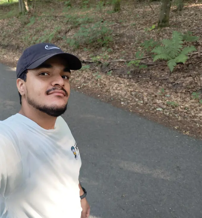 Abdulaziz taking a selfie in a Nike hat against a forest background