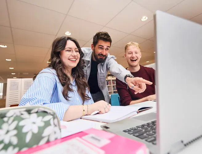 CHE university students collaborating and studying together on a laptop campus project.