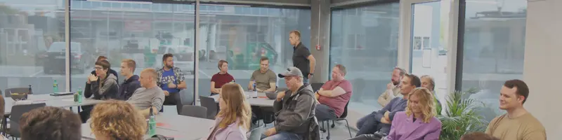 People sitting spread out across the room, listening to someone out of frame.