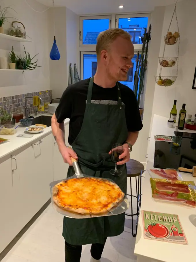 Emil holding a fresh-baked pizza in his kitch