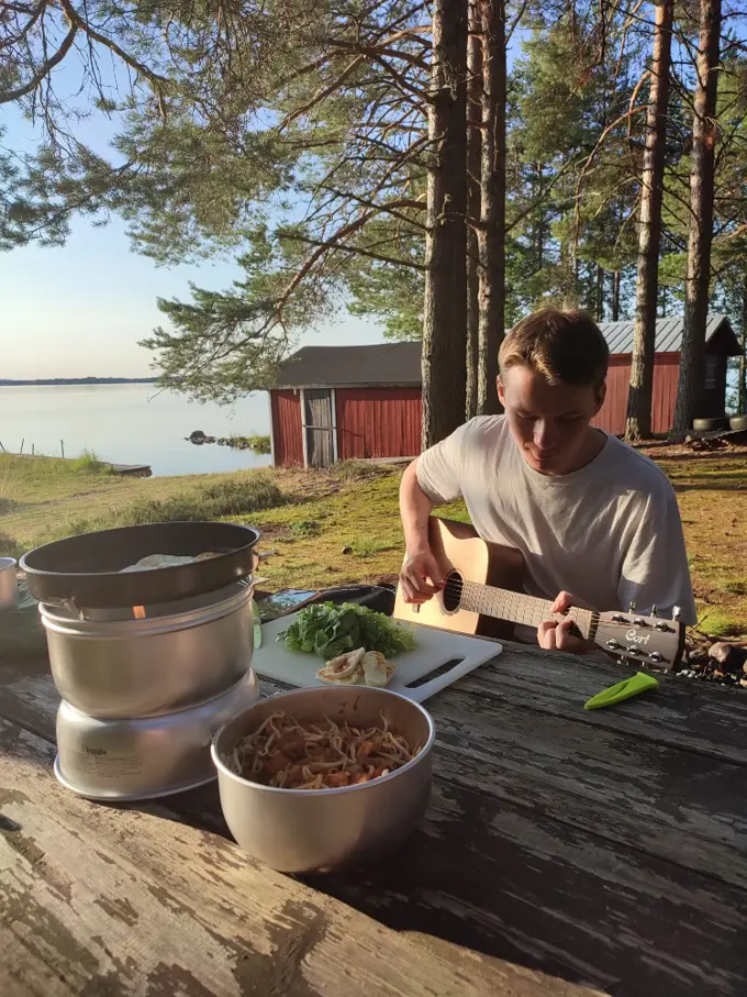 Jesper Moller Jensen playing guitar outside near a cabin