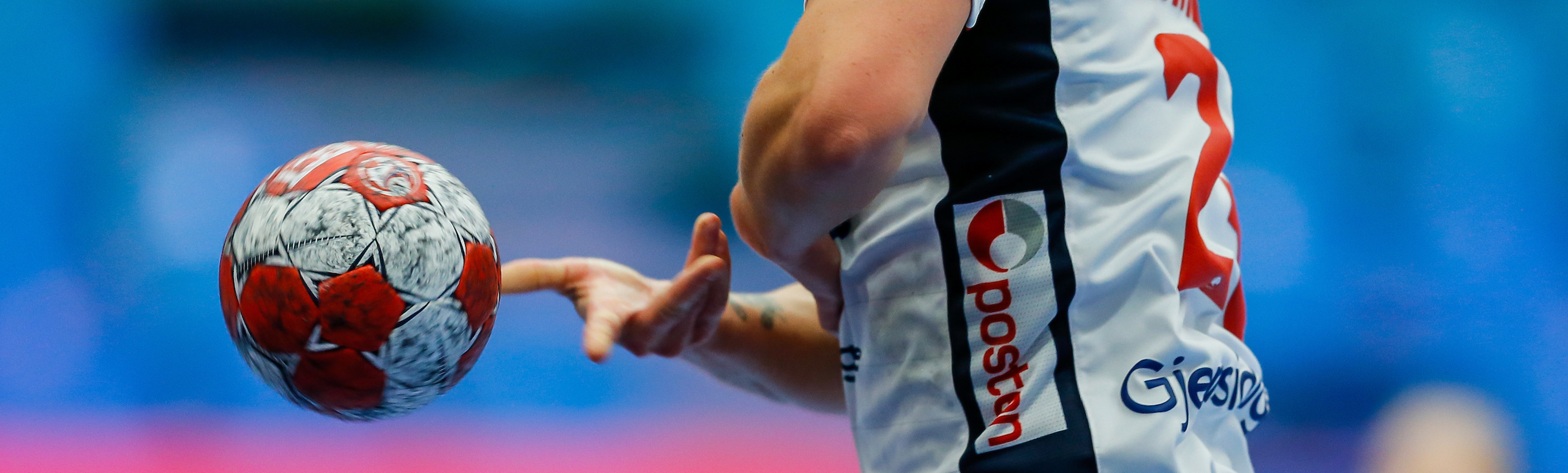 Close-up of professional handball player holding official red and white ball during an EHF tournament match.