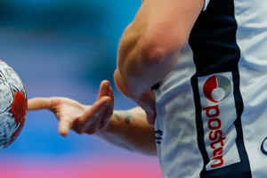 Close-up of professional handball player holding official red and white ball during an EHF tournament match.
