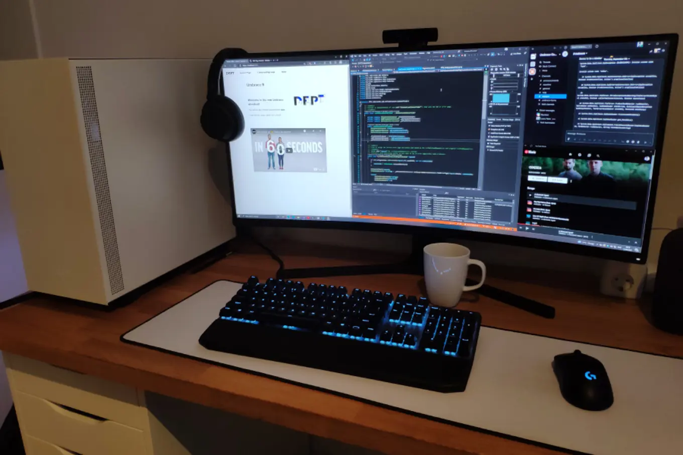 Laura's work from home setup. She has a large horizontal screen with headphones hanging on the side.