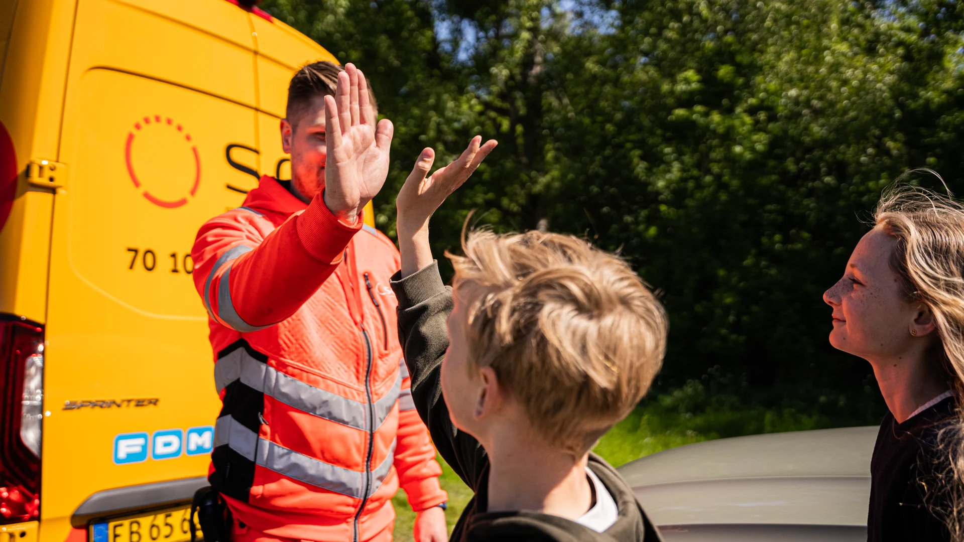 SOS Dansk Autohjælp roadside assistance worker offering emergency car repair and family support on European road trips.