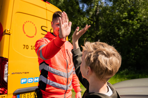 SOS Dansk Autohjælp roadside assistance worker offering emergency car repair and family support on European road trips.