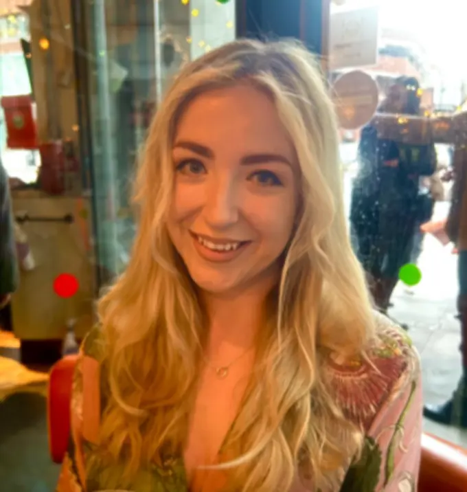 Profile picture of Amy Czuba, with a smiling, happy face and long, wavy blond hair, wearing a pink and green floral dress.