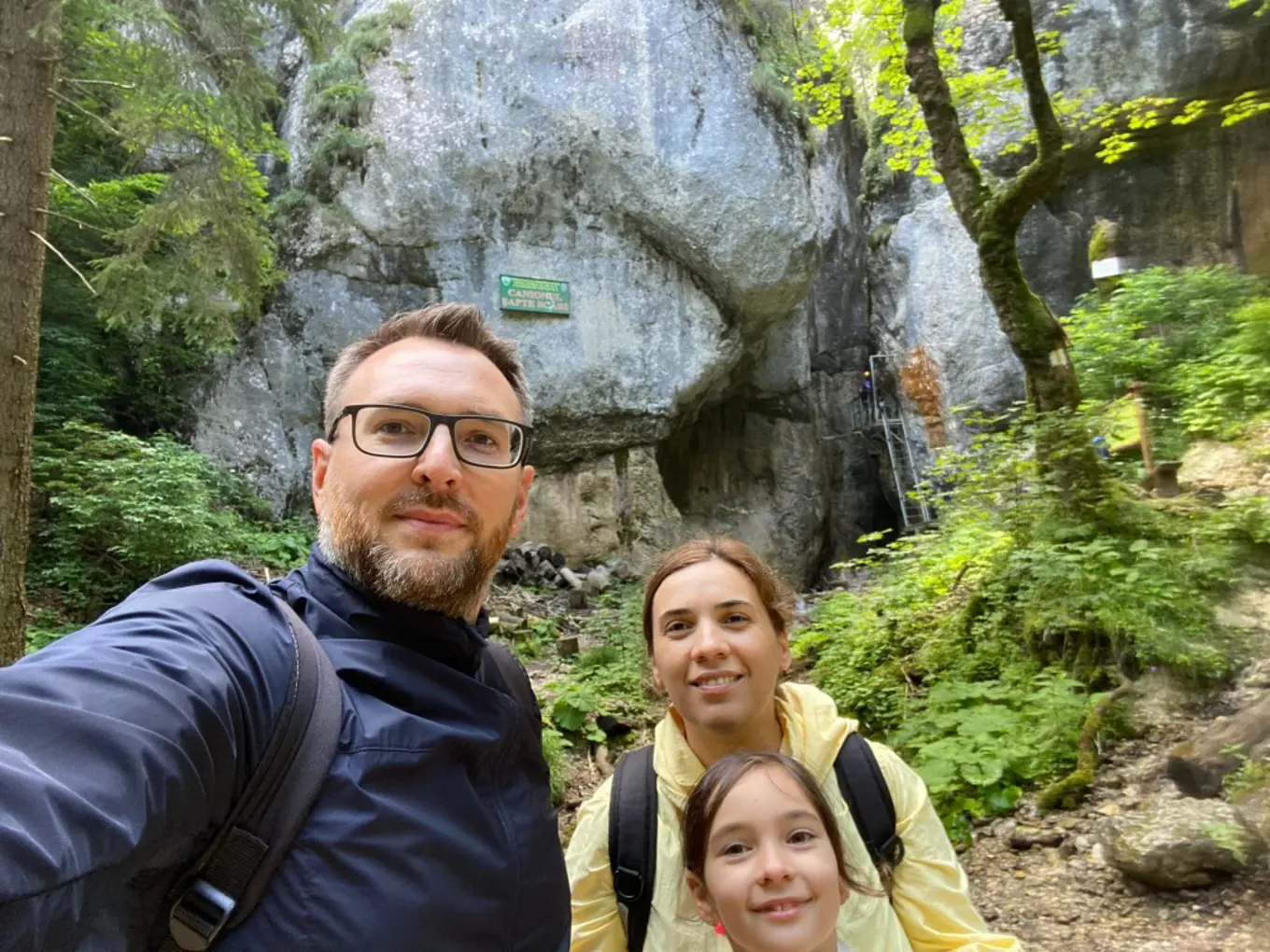 Adrian and his family in front of a stone cliff face in a forest