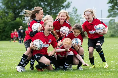 Group of girls from football team holding balls and laughing 
