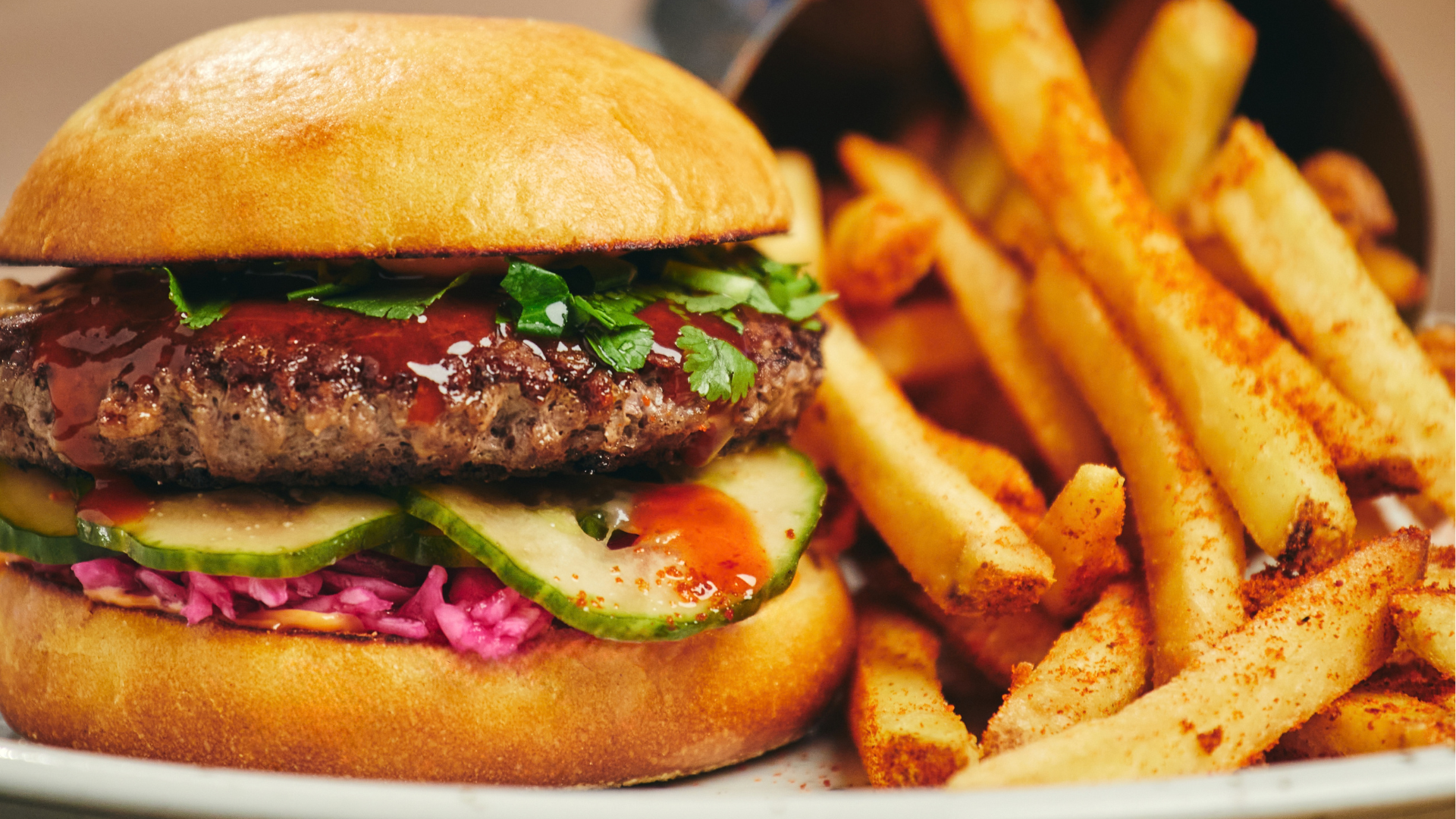 Delicious gourmet burger with fresh toppings and seasoned french fries served on a plate.