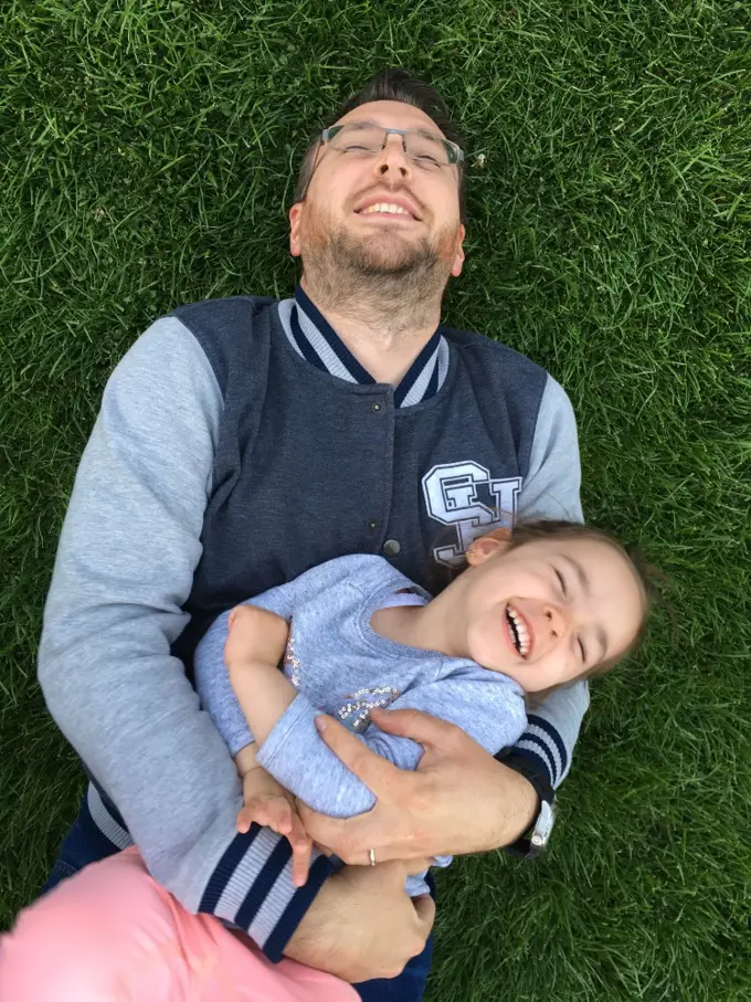 Adrian lying in the grass with his daughter