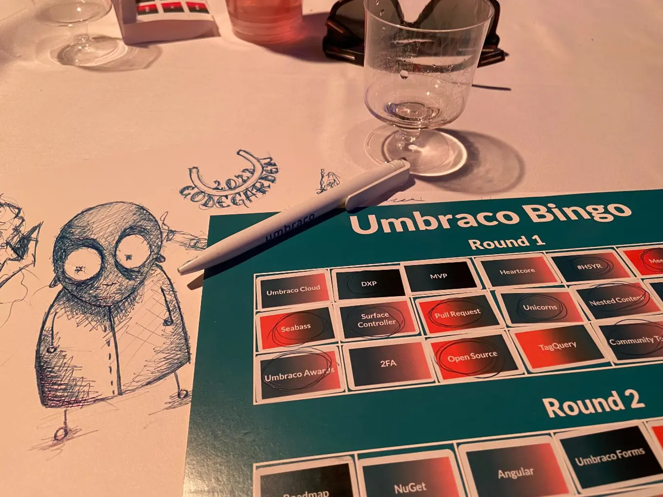 Yoana's Umbraco Bingo card is filled out as she plays along. On a sheet of paper on the side, there are some doodles.