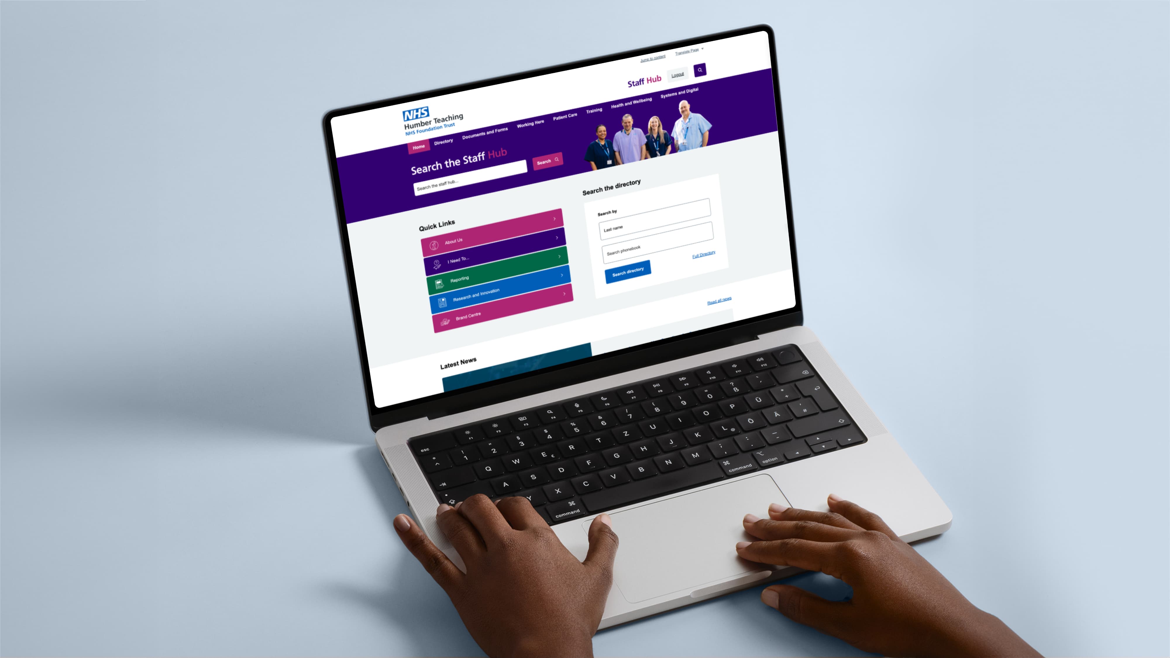 A laptop displaying the Humber Staff Hub intranet homepage, featuring a directory search and quick links, being used in a workspace.