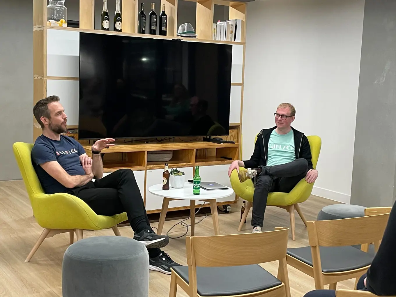 Filip and Kristian are sitting on two bright yellow chairs. Filip is answering a question from the audience, while Kristian listens on.