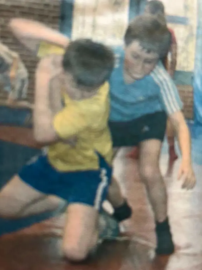 A blurry image of two young white boys, one in a yellow shirt and the other in a blue shirt, wrestling.