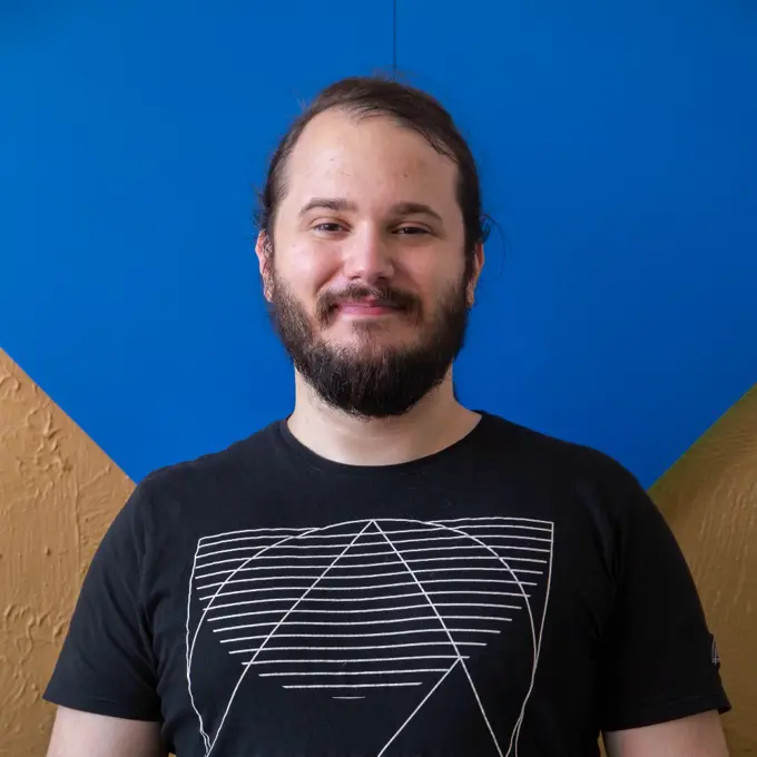 Arton Agroni headshot with black shirt and blue background