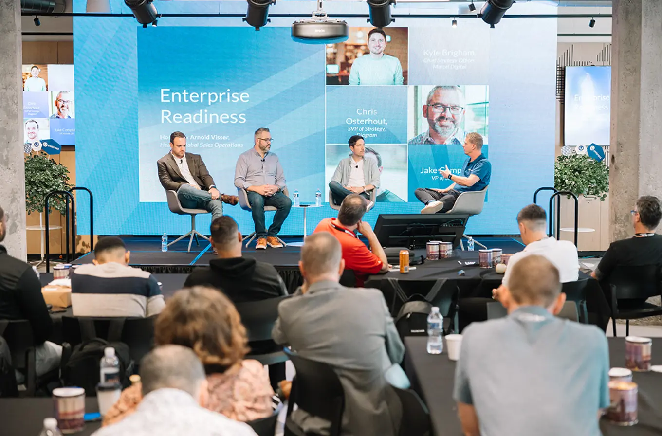 A growd of four men are seated on chairs on a stage business setting