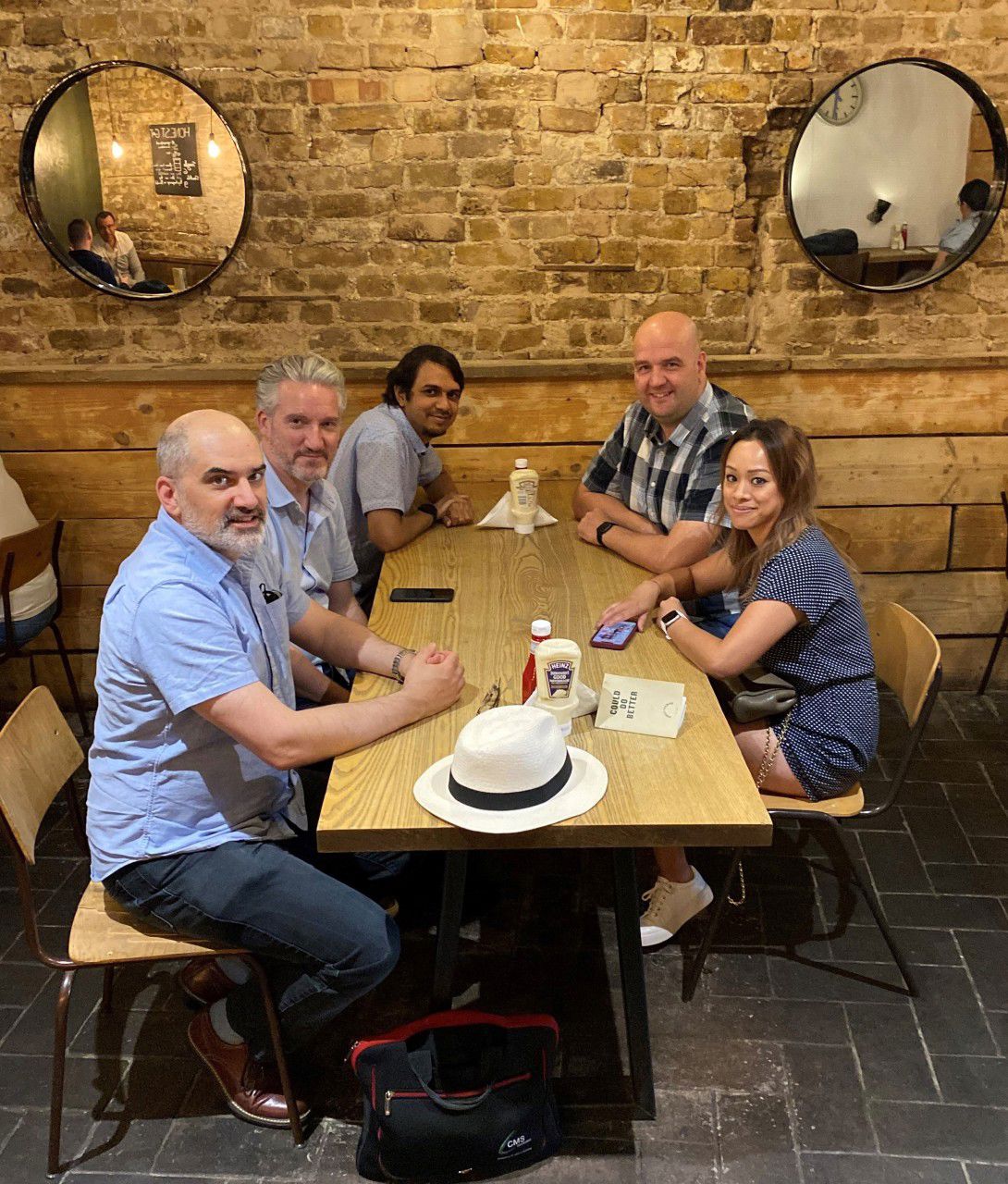 Five people from the Moriyama Team sitting around a table, posing for the camera