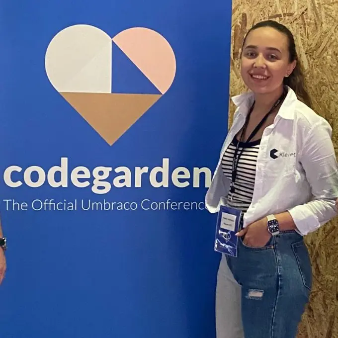 Yoana stands with her hands casually in her pockets, next to the Codegarden sign.