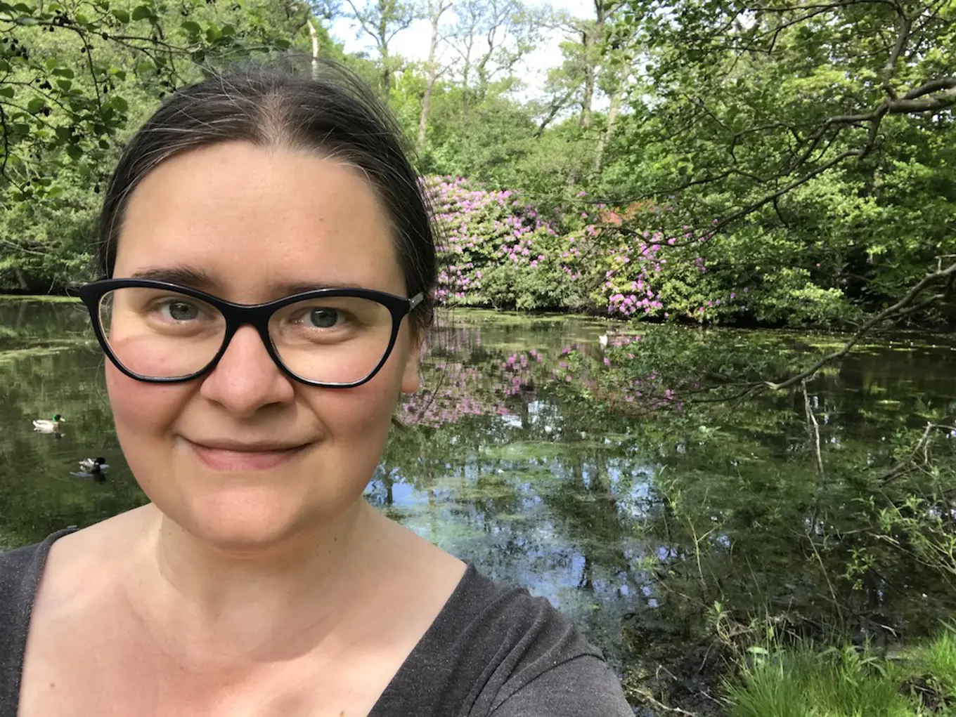 Julia in front of a pond and greenery