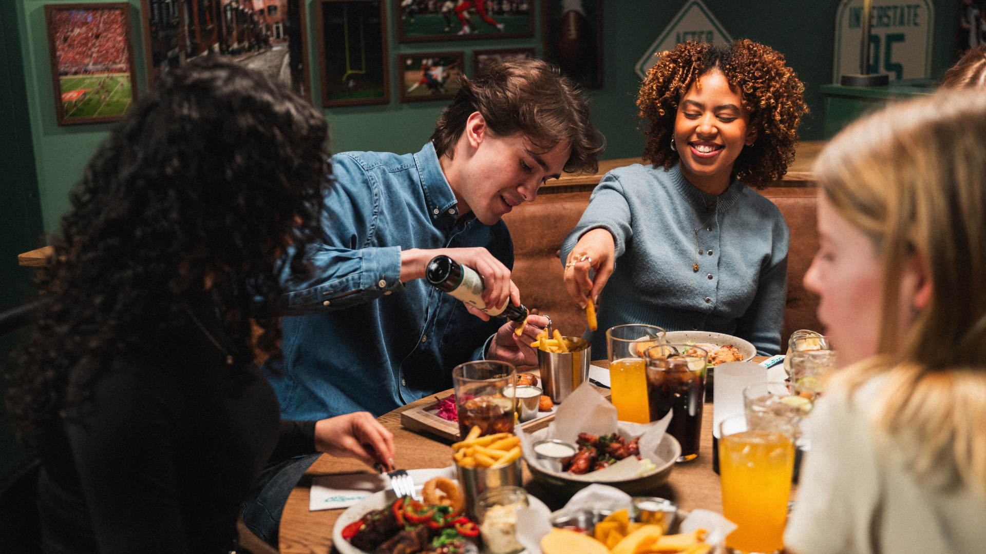 Group of friends enjoying drinks, french fries, and appetizers together at a casual dining sports bar.