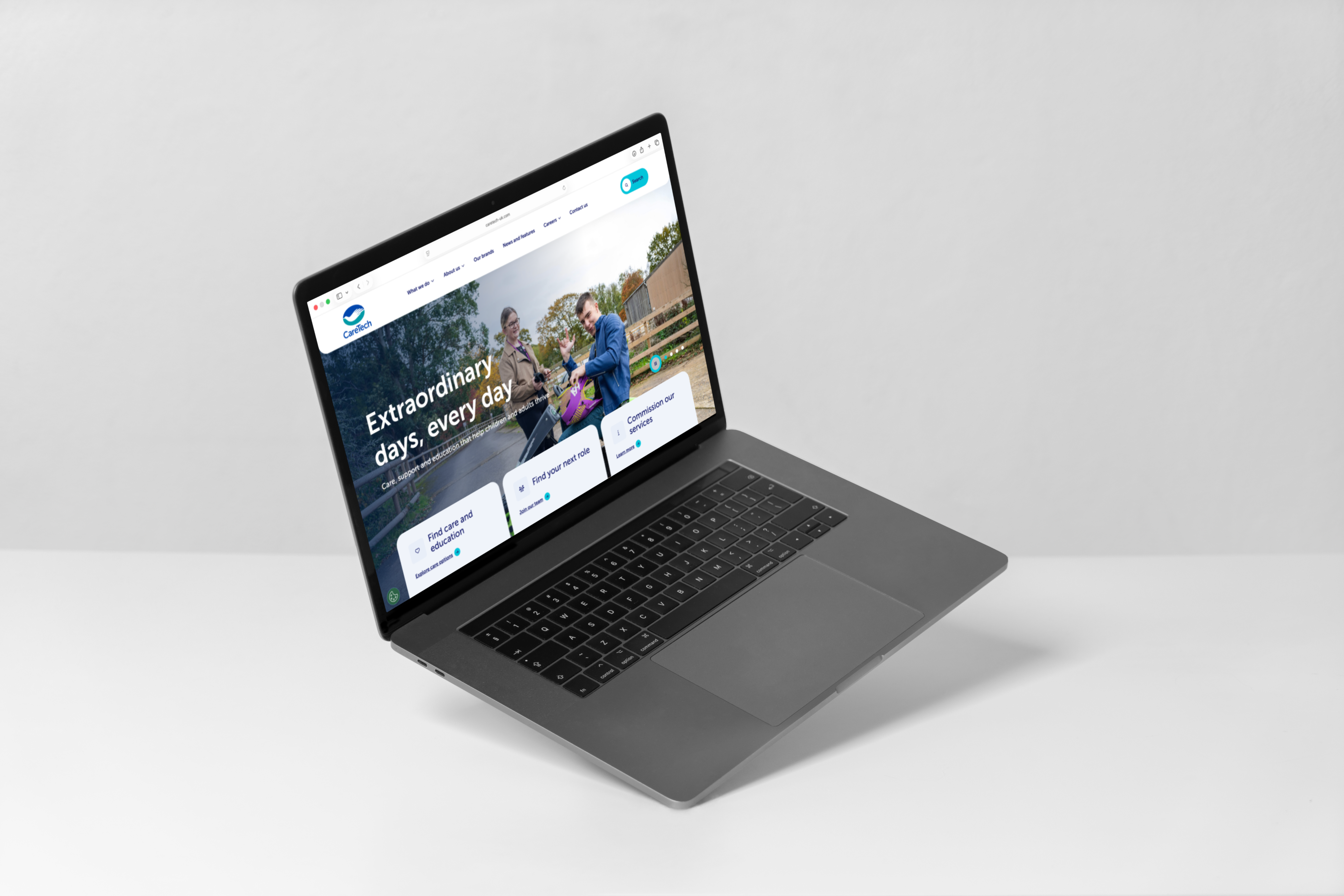 A laptop at a side-profile angle displaying the CareTech desktop homepage, featuring the headline "Extraordinary days, every day" and service navigation tiles.