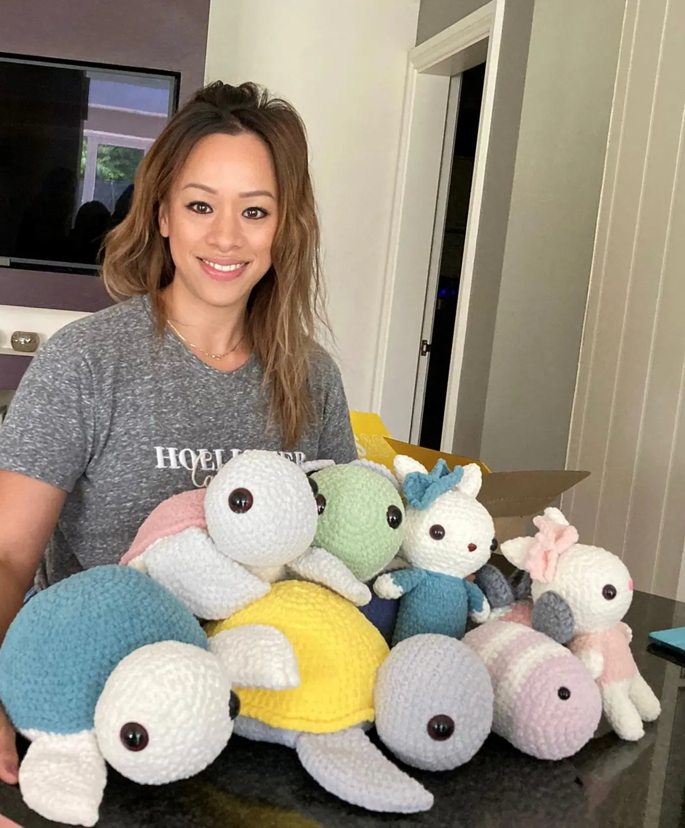 Thuy smiles at the camera with her crotchet friends, from bunnies to turtles and bees, in bright pastel colours.