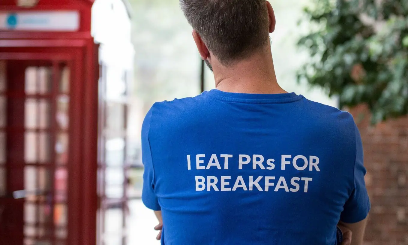 Person with their back to the camera. On the t-shirt is written "I eat PRs for Breakfast"