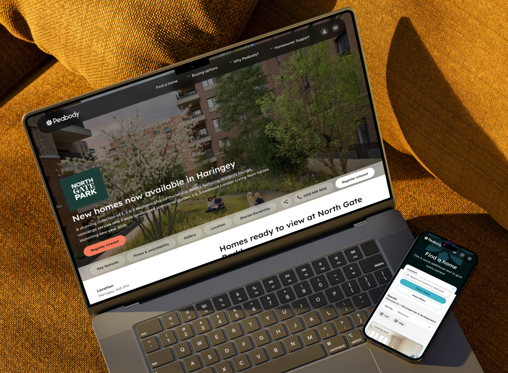 A laptop and smartphone resting on a yellow surface, both displaying the Peabody website page for "North Gate Park" homes in Haringey.